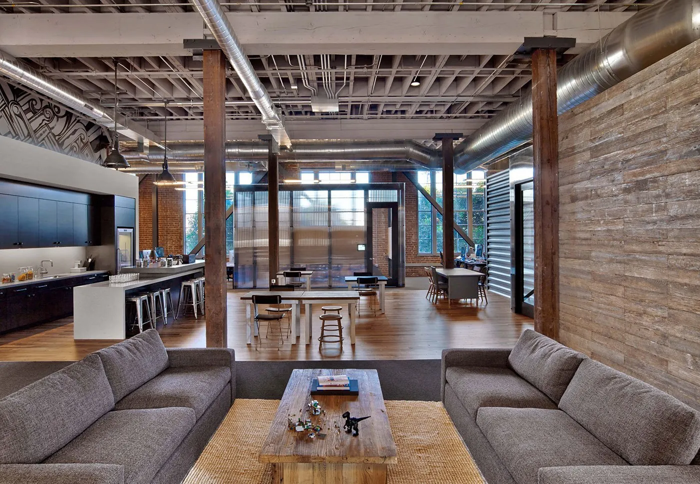Converted loft office with timber columns, exposed ductwork and a lounge